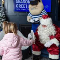 Girl hands coloring sheet to Santa